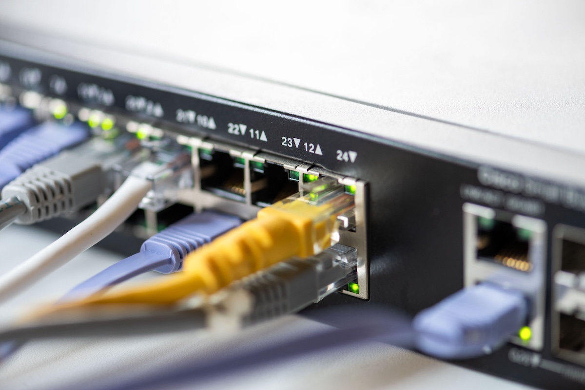 Close-up of a network switch with multiple colored Ethernet cables connected, indicating active data transfer with glowing LED indicators